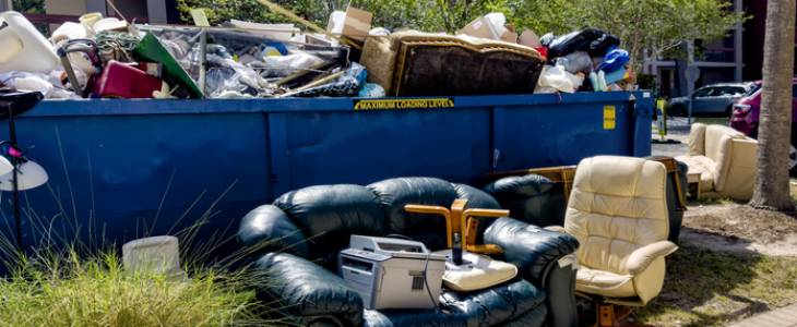 Dumpster overflowing with junk and furniture.