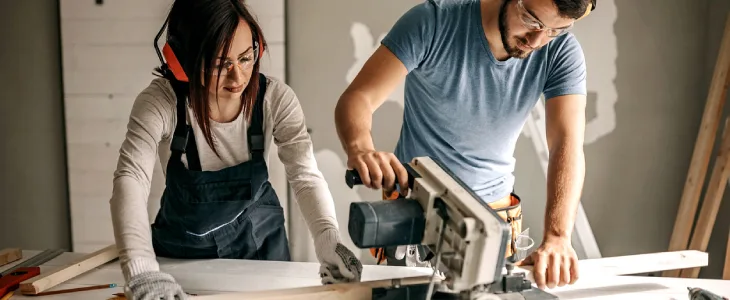 Couple cutting wood with a miter saw
