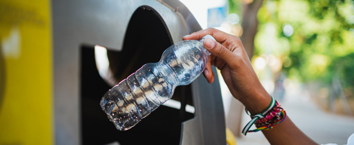 Woman putting plastic bottle in a recycling bin