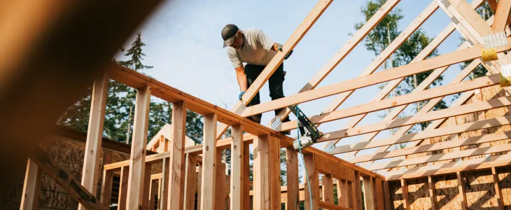 Construction worker building wooden roof frame on a house.