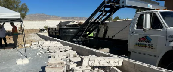 Demolition site with broken concrete blocks beside an Eclipse truck.
